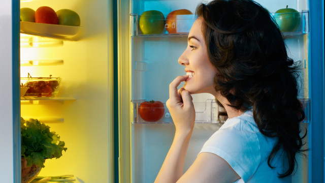 a hungry girl opens the fridge