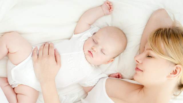 Young mother and her baby, sleeping in bed