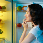 a hungry girl opens the fridge