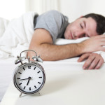 Young attractive man sleeping on bed early morning