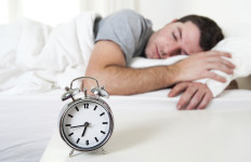 Young attractive man sleeping on bed early morning