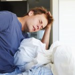 Young man waking up and discovering he has chronic back pain