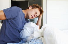 Young man waking up and discovering he has chronic back pain