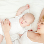 Young mother and her baby, sleeping in bed